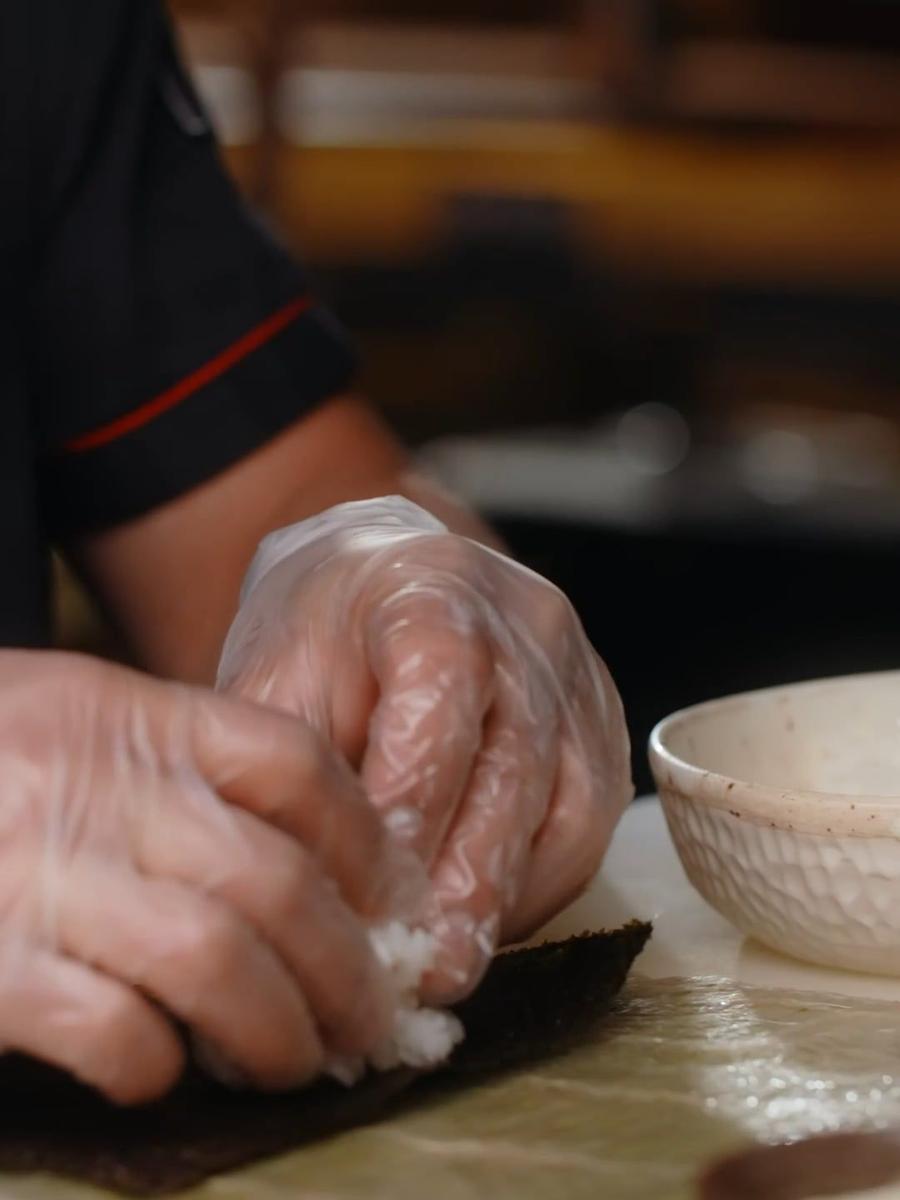 Hands shaping sushi rice at a counter
